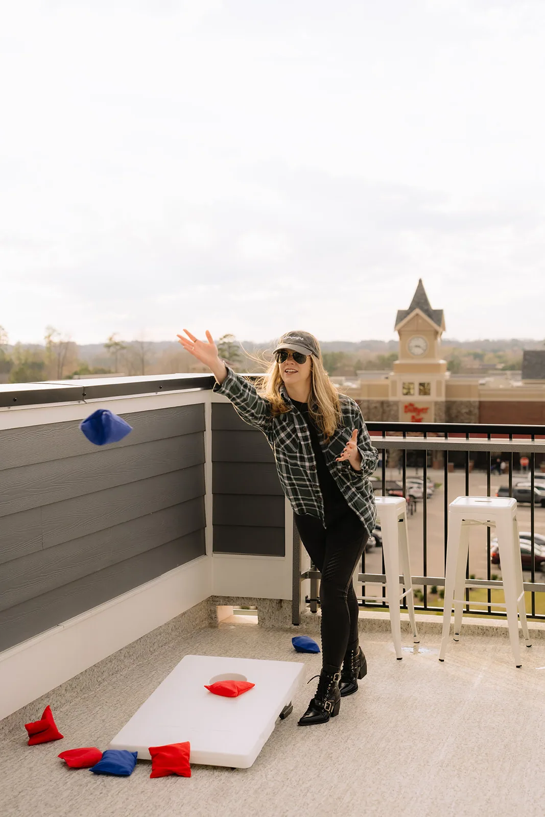 Bean bag in mid air above a cornhole board on a rooftop deck