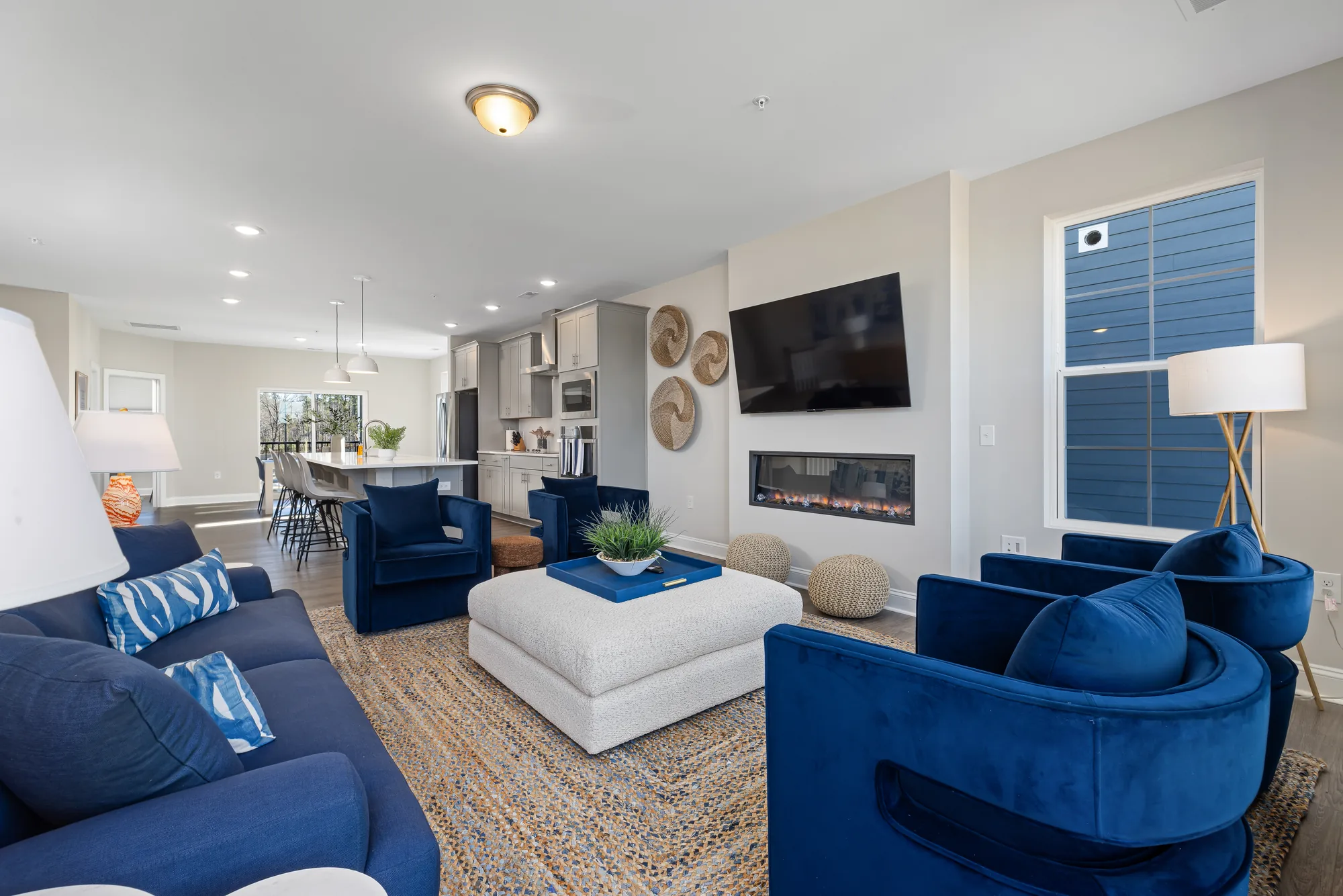 Blue velvet swivel chairs and sofa around a white ottoman facing a linear fireplace and TV