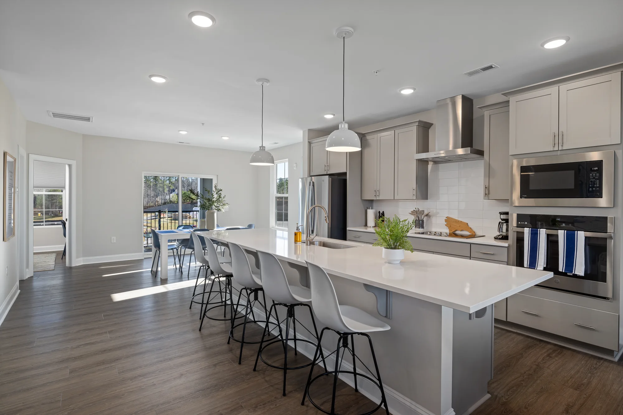 Julianne kitchen with wall ovens, a stainless hood and a long island with stools