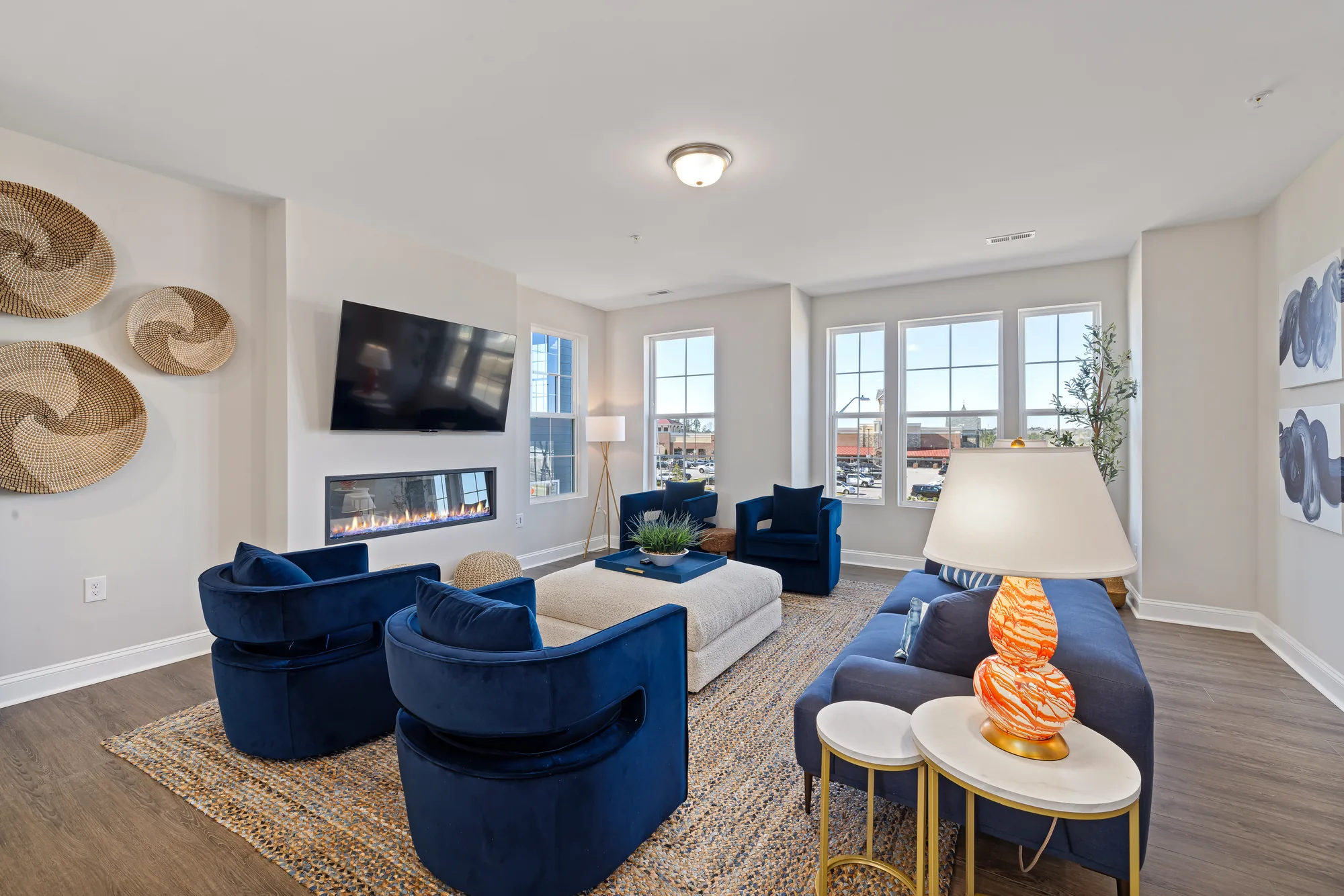 Living room with blue seating, a white ottoman and woven wall discs, tighter crop