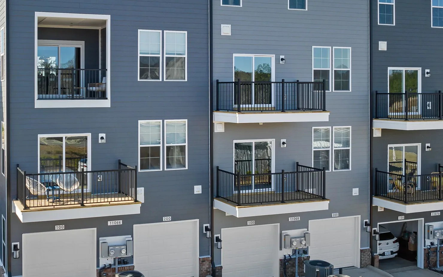 Angled drone view of the rear of the building, every unit with its own balcony and garage