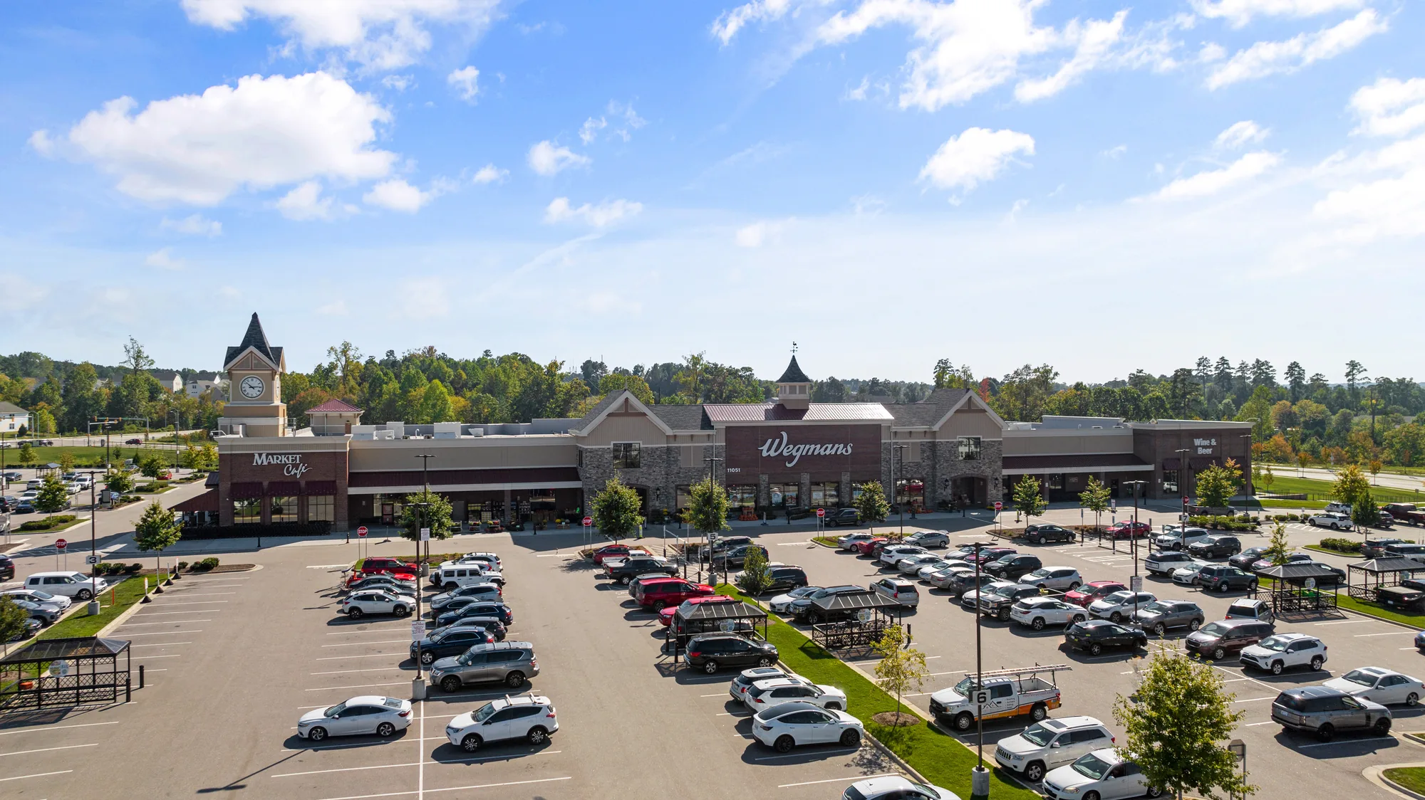Aerial over the neighboring retail cluster with its clock tower, storefronts and parking
