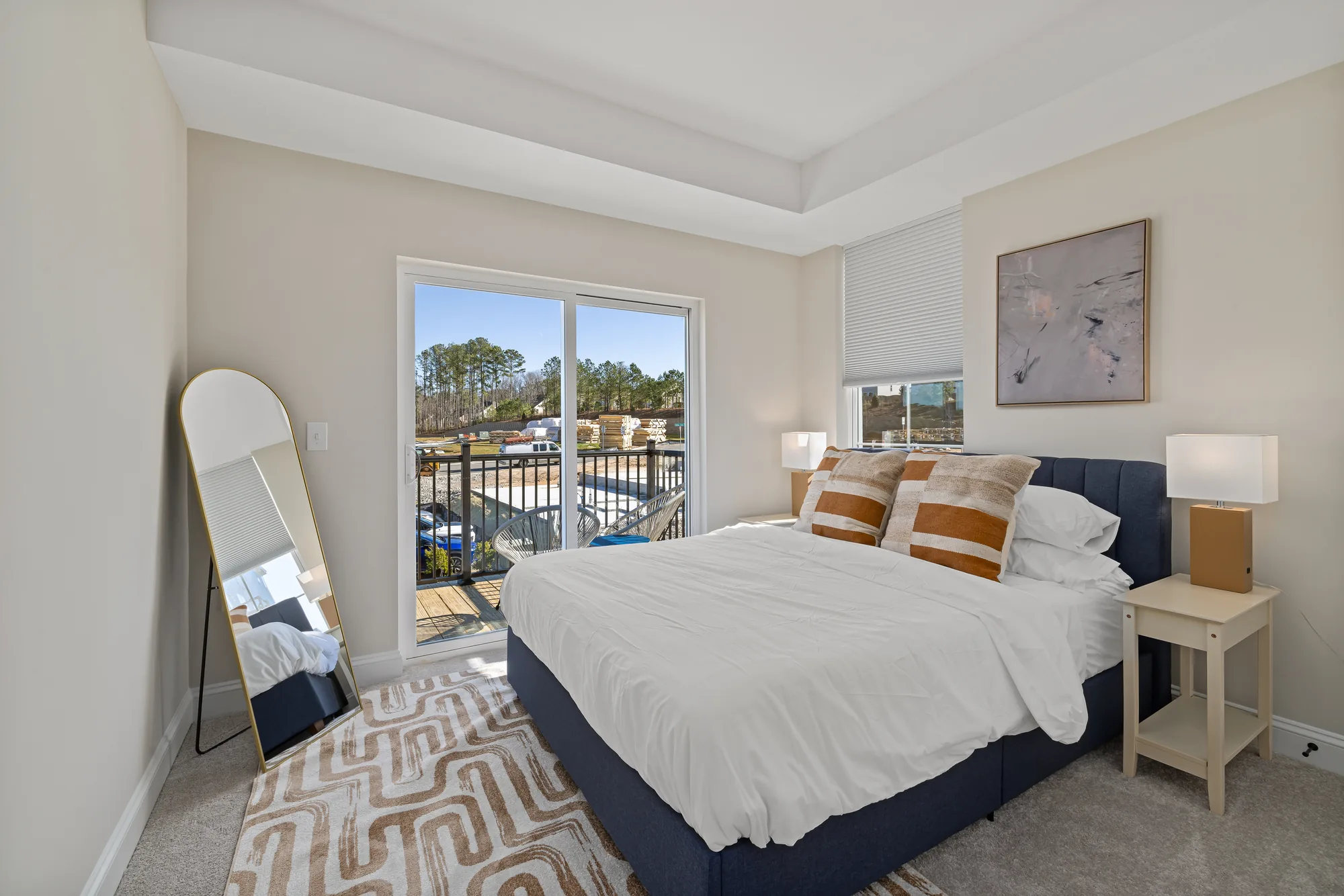 Bedroom with a navy bed, a leaning mirror and a sliding door onto the balcony